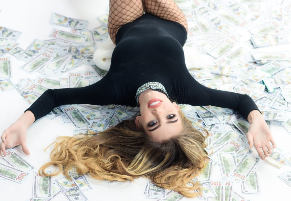 financial domination sexy woman lying on bed of money
